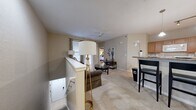This single-story residence features a thoughtfully arranged floor plan that maximizes its well-proportioned footprint. The open-concept living, dining, and kitchen area forms the central hub of the home. The living room is finished with plush carpet and features a ceiling fan, while a breakfast bar with pendant lighting and bar stool seating connects the living space to the kitchen. The kitchen is equipped with warm wood cabinetry, granite-style countertops, hardwood-style flooring, a full suite of white appliances, and track lighting overhead. A dedicated dining area provides additional space for sit-down meals.

The primary bedroom is a comfortable, carpeted retreat with a dedicated closet featuring louvered doors. The second bedroom is equally well-appointed with soft carpeting and access to a closet. Both bedrooms offer neutral tones conducive to relaxation.

The two bathrooms are distinct in design: one features a full tub-shower combination with white tile surround, while the other offers a glass-enclosed walk-in shower, a single-sink vanity with wood cabinetry, and hardwood-style flooring. A private exterior door from the living area provides convenient outdoor access, completing this functional and cohesive layout.