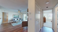 This single-floor residence offers a thoughtfully designed layout that balances comfort and functionality throughout. The living room serves as the heart of the home, featuring rich hardwood flooring, a ceiling fan, and expansive sliding glass doors that flood the space with natural light and open to a private balcony overlooking a serene waterfront setting with lush greenery. The open, airy ambiance makes the living area feel generously spacious.

Adjacent to the living room, the dedicated dining area is defined by hardwood flooring, a stylish pendant light fixture, and a bright window that adds to the warm, inviting atmosphere. The kitchen is well-equipped with stainless steel appliances — including a range, over-the-range microwave, and refrigerator — complemented by light wood cabinetry and dark granite-style countertops.

The residence includes two bedrooms, each with ceiling fans, carpeted flooring, and windows that invite natural light. The primary bedroom offers a calm retreat, while the secondary bedroom is cozy and well-proportioned. Both bathrooms feature tub-shower combinations with white tile surrounds, dark countertops, and hardwood-style flooring, providing clean and functional spaces. A textured ceiling is consistent throughout, adding a classic residential character to the entire home.
