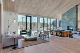 Located at 1810 N 25th Ave in Bozeman, Montana, this expansive single-story amenity facility offers a thoughtfully designed space for recreation, fitness, and community gathering. The architecture blends warm natural wood ceilings with clean white walls, light hardwood flooring, and floor-to-ceiling black-framed windows that flood the interiors with natural light and frame striking views of the surrounding Montana landscape and outdoor pool area.

The fitness center is a standout feature, boasting soaring vaulted ceilings with wood detailing and an extensive array of professional-grade equipment, including rowing machines, stair climbers, cable systems, power racks, resistance machines, dumbbells, kettlebells, and medicine balls. Full-length mirrors and large windows ensure the gym feels open and connected to the outdoors.

The lounge and social areas are equally impressive, featuring a dramatic living room with high vaulted ceilings, a large leather sofa, and oversized glass doors opening to the pool deck. A formal dining area accommodates large groups beneath a sculptural pendant light cluster. A quieter seating nook with leather chairs and curated artwork provides an intimate retreat. Well-appointed hallways with modern cabinetry, marble-accented kitchen elements, and lush indoor plants complete this polished, community-centered facility.
