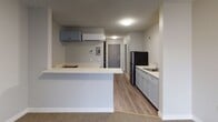 Located at 3350 Rose Cranes in San Diego, unit #139 is a single-floor residence that combines practical design with a clean, neutral aesthetic throughout. The entry foyer welcomes residents with wood-look flooring and a sliding mirrored closet, offering convenient storage from the moment you step inside.

The kitchen is efficiently laid out with gray cabinetry, a white countertop with an integrated sink, and a black refrigerator. A peninsula counter separates the kitchen from the adjoining living area, creating a natural open-concept flow between the two spaces. An overhead wall-mounted mini-split unit provides climate control. Upper cabinetry adds additional storage above the counter space.

The living area features patterned carpet flooring and neutral-toned walls, creating a calm and versatile space. A full-width sliding glass door fitted with vertical blinds allows natural light to fill the room while providing access to an outdoor area and views beyond.

The bathroom features tile flooring, a white vanity with under-sink cabinetry, a round mirror, and a toilet, all framed by a paneled gray door. A separate shower area is also present. Throughout the unit, textured ceilings and flush-mount lighting provide consistent, practical illumination.