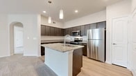 This well-appointed single-floor unit offers a thoughtfully designed layout that maximizes functionality across its comfortable footprint. The open-concept kitchen and living area serves as the heart of the home, where light hardwood-style flooring anchors a contemporary kitchen outfitted with dark espresso cabinetry, granite countertops, a subway tile backsplash, and a full suite of stainless steel appliances including a refrigerator, range, and built-in microwave. A central island with an integrated sink and pendant lighting above adds both prep space and visual appeal. The adjacent living area transitions seamlessly to soft carpeting, creating a warm and inviting atmosphere.

The bedroom is a generously sized retreat finished with plush carpet and access to a well-organized walk-in closet featuring wire shelving and a built-in shelving tower. The full bathroom continues the unit's cohesive design language with matching dark cabinetry, granite countertops, a large vanity mirror, and light hardwood-style flooring. A dedicated in-unit laundry area with a full-sized Whirlpool washer provides added everyday convenience. The overall aesthetic is clean, modern, and move-in ready.