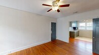 Located in Columbia, SC, this 2-bedroom, 1-bathroom single-floor home offers a thoughtful layout with classic charm and updated finishes throughout. Rich hardwood floors flow seamlessly across the living areas and bedrooms, complemented by clean white walls and ceiling fans in every room.

The living room is a standout space, centered around a traditional wood-burning fireplace with a white painted mantel and flanked by windows that fill the room with natural light. A charming paneled front door adds character to the entry.

Both bedrooms are well-proportioned and bright, each featuring multiple windows with white blinds that allow ample sunlight in, along with ceiling fans for year-round comfort. The primary bedroom includes two interior doors — one leading to a closet and another to the hallway — and is dressed with crown molding for an added touch of refinement.

The kitchen has been tastefully updated with gray cabinetry, a penny tile backsplash, stainless steel appliances, a single-basin sink, and track lighting overhead. Light wood-look tile flooring contrasts nicely with the warm hardwood found in the rest of the home.

The bathroom features a tub/shower combination surrounded by large-format marble-look wall tiles, giving it a clean, modern aesthetic. A connecting hallway ties all rooms together efficiently, making for a cohesive and functional floor plan.