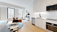 Located on the prestigious Rue Sherbrooke Ouest in Montréal, this thoughtfully designed studio offers a refined urban living experience within a compact, efficiently utilized floor plan. The open-concept layout seamlessly integrates the kitchen, dining, and living areas, creating a cohesive and functional living environment. The modern kitchen is outfitted with floor-to-ceiling white cabinetry, a black matte faucet, an undermount sink, a built-in oven, an induction cooktop, a stainless steel dishwasher, and an over-the-range microwave — all set against clean white countertops and light hardwood flooring that extends throughout the space. Large windows invite abundant natural light and frame views of the surrounding Montréal cityscape, enhancing the sense of openness. The sleeping area accommodates a full-sized bed and benefits from its own generous windows, maintaining the bright and airy atmosphere of the unit. The bathroom features large-format neutral tile flooring, a floating vanity with matte black hardware, a backlit mirror cabinet, and a clean, minimalist aesthetic. Throughout the space, a consistent white and neutral palette paired with modern black accents creates a polished, contemporary ambiance ideal for urban living.