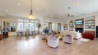 Located at 1000 Oak St. in Reynoldsburg, Ohio, this well-appointed single-floor space offers a generous and versatile layout designed for both comfort and functionality. The interior is finished with light hardwood-style flooring throughout, crown molding, and recessed lighting that contribute to a clean, contemporary aesthetic.

The expansive open-concept living area serves as the heart of the space, anchored by a tile-surround gas fireplace flanked by built-in shelving with lower cabinetry — ideal for displaying décor and housing media. A wall-mounted TV sits above the fireplace, and a modern ceiling fan adds to the room's comfort. Large windows flood the space with natural light and offer views of the surrounding neighborhood. French doors with glass grid panels provide an elegant transition between zones.

The dining area is bright and inviting, featuring oversized windows with transom panels above, a contemporary pendant light, and a sleek dining table with upholstered seating. Adjacent to it, a dedicated coffee bar station adds a welcoming, hospitality-focused touch.

The reception area features a clean white counter and opens directly to the kitchen, which is equipped with warm wood cabinetry, a full-size refrigerator, microwave, and a small dining counter. A private conference or meeting room with carpeted flooring and dual windows rounds out the functional offerings of this well-organized space.