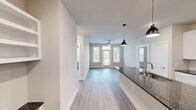 This thoughtfully designed 2-bedroom, 2-bathroom residence in Austin, TX offers a clean, modern aesthetic throughout its single-floor layout. The open-concept living and dining area is anchored by light wood-tone flooring, neutral walls, and abundant natural light streaming through multiple windows and a glass door that opens to the outdoors. Pendant lighting and a ceiling fan add functional style to the space.

The kitchen is well-appointed with crisp white shaker cabinetry extending to the ceiling for ample storage, dark granite countertops, a full suite of stainless steel appliances including a range, microwave, and refrigerator, and a peninsula that connects seamlessly to the living area.

Both bedrooms are generously sized with ceiling fans, wood-tone flooring, and large windows. Each bedroom is paired with its own walk-in closet featuring multi-level shelving and hanging rods for organized storage.

The two bathrooms mirror the home's refined finishes, showcasing white cabinetry, granite-topped vanities, and tile flooring. The primary bathroom includes a dual-sink vanity with a large framed mirror, while the second bathroom features a glass-enclosed shower. The overall ambiance is bright, clean, and move-in ready.