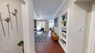 This thoughtfully designed 1-bedroom, 1-bathroom residence offers a cohesive open-concept layout that seamlessly connects the kitchen, dining, and living areas. Rich hardwood-style flooring runs throughout the main living spaces, complemented by crown molding and neutral gray tones that lend a modern, polished feel.

The galley-style kitchen features white cabinetry, dark granite-style countertops, a double sink, and black stainless appliances, including a refrigerator, range, and microwave. It opens naturally to the dining area, which is bathed in natural light from large windows fitted with white blinds and sheer curtains, creating a bright and airy atmosphere.

The living room is anchored by a ceiling fan, a bold accent wall in deep gray, and a built-in display shelf that adds both function and character. Multiple windows allow ample natural light to fill the space.

The bedroom is a serene retreat with soft carpet, a ceiling fan, and windows that invite natural light. It connects to a spacious walk-in closet outfitted with wire shelving and hanging rods. The full bathroom features hardwood-style flooring, a long granite-topped vanity with white cabinetry, a large mirror, and a shower-tub combination. The unit also includes a dedicated laundry area and hallway for added convenience.