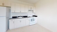 Located at 405 East 7th St, Unit 307 in Hialeah, Florida, this single-floor residence features a bright, clean interior with a cohesive white color palette throughout. Light-toned tile flooring runs seamlessly across the living and kitchen areas, creating a fresh and airy atmosphere.

The open kitchen is well-equipped with white cabinetry extending to the ceiling for ample storage, dark granite-style countertops, a stainless steel sink, a white electric range with overhead ventilation, and a full-size refrigerator. The kitchen opens directly to the living area, which offers a comfortable and functional layout bathed in ambient ceiling light.

The bedroom is a calm, light-filled space featuring a window with an outdoor view of greenery, white tile flooring, and a closet with wire shelving for organized storage.

The bathroom maintains the clean aesthetic of the rest of the unit, featuring white tile flooring, a full soaking tub with an overhead shower, a toilet, and a small window that introduces natural light and ventilation.

The entryway is straightforward and functional, leading naturally into the main living space. Overall, the unit presents a well-maintained, move-in-ready interior with a minimalist design sensibility suited to practical, comfortable living in Hialeah, FL.