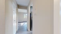 Located at 565 Aldine St in Saint Paul, Minnesota, this two-bedroom, one-bathroom residence offers a well-organized single-floor layout with a clean, modern aesthetic. The living room is a bright, open space anchored by large windows that frame views of mature trees outside, allowing generous natural light to fill the room. Light gray wood-style flooring extends throughout the main living areas, complementing the neutral warm-toned walls and white trim.

The kitchen is a standout feature, showcasing updated gray shaker-style cabinetry, marble-look countertops, a modern faucet, and stainless steel appliances including a refrigerator, range, and over-range microwave. Light wood-style flooring ties the kitchen together with the rest of the home.

Both bedrooms are comfortably proportioned, with carpet flooring, large windows with outdoor views, and baseboard heating. The primary bedroom offers generous closet storage with louvered bifold doors. The second bedroom also includes closet access. Multiple closets throughout the unit provide ample storage.

The bathroom features full white tile wall surround, a soaking tub, and a medicine cabinet mirror. A central hallway connects all rooms, creating a practical and efficient flow. The unit includes baseboard heating throughout.