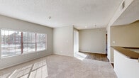 This 1-bedroom, 1-bathroom residence is thoughtfully arranged across a single floor, offering a functional and comfortable layout. The living room is a bright, open space featuring plush wall-to-wall carpeting, a textured ceiling, and a large window fitted with horizontal blinds that invite generous natural light. A pass-through counter with dark granite-style surfaces connects the living area to the kitchen, creating an open sightline between the two spaces. The kitchen is equipped with white shaker-style cabinetry, dark granite-style countertops, a white subway tile backsplash, and black appliances including an electric range, over-the-range microwave, refrigerator, and dishwasher, all set on wood-look flooring. The spacious bedroom features soft carpeting, a ceiling fan, a large window, and direct access to both a walk-in closet with built-in shelving and the full bathroom. The bathroom includes a dark granite-topped vanity with a framed mirror, a tub-shower combination, wood-look flooring, and recessed lighting. A dedicated entrance and hallway complete the layout, providing an organized and efficient flow throughout the home.