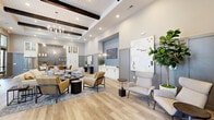 Located in Windsor Cay, Clermont, FL, this thoughtfully designed single-floor community living room offers a welcoming and versatile gathering space. The room immediately impresses with its soaring ceilings adorned with striking dark wood exposed beams set against a white shiplap ceiling, complemented by a statement chandelier and recessed lighting throughout.

Light wood-toned flooring runs throughout the open-plan layout, lending warmth and continuity to the space. Multiple distinct seating areas are arranged to encourage both social interaction and quiet relaxation, featuring a curated mix of neutral-toned sofas, accent armchairs in soft grey and gold, and stylish area rugs. A row of tall windows along one wall floods the space with natural light and views of the surrounding outdoors.

A built-in kitchenette area includes floor-to-ceiling white cabinetry with glass-front uppers, a metallic tile backsplash, open shelving, and a dining table with leather chairs. A decorative blue-accented niche with wall sconces and a white credenza serves as a design focal point. Additional furnishings include high-back lounge chairs, a shuffleboard table, and intimate conversation groupings. Wainscoting in muted grey adds architectural refinement throughout, creating a polished, resort-inspired ambiance.