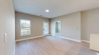 Located at 300 Iron Way, Unit 203 in Marysville, Ohio, this well-appointed 2-bedroom, 2-bathroom residence offers a thoughtfully designed single-floor layout. The open-concept kitchen and living area serves as the heart of the home, featuring light hardwood-style flooring, recessed lighting, and large windows that invite natural light. The kitchen is outfitted with white shaker cabinetry accented by black hardware, stainless steel appliances including a range, microwave, and refrigerator, a decorative tile backsplash, and a center island with a sink and pendant lighting above. A hallway connects the main living area to the private quarters, flanked by doors leading to additional rooms. The two bedrooms offer plush carpeting, neutral-toned walls, and windows with outdoor views. The primary bedroom includes a spacious walk-in closet with built-in shelving. The bathrooms are finished with large-format tile, and one features a walk-in shower with sleek black-framed glass doors. Additional highlights include three closets, a dedicated laundry area, a pantry, utility room, and a private balcony accessible from the living area, providing a comfortable outdoor retreat.