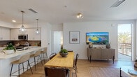 This single-floor residence in San Diego's Scripps Ranch neighborhood offers a thoughtfully designed open-concept layout with modern finishes and a cohesive, neutral color palette. The living and dining area flows seamlessly together, featuring light wood-style flooring, crisp white walls, and access to an outdoor balcony that brings in natural light. The dining space accommodates a full-size table, while the living area provides a comfortable setting anchored by clean architectural lines.

The kitchen is outfitted with stainless steel appliances, including a gas range and over-the-range microwave, complemented by white cabinetry, quartz countertops, and a tasteful tile backsplash. A breakfast bar with pendant lighting adds a functional yet stylish touch.

The bedrooms are carpeted for comfort, each featuring windows with blinds that allow for natural light and privacy. The primary bedroom includes direct access to an en-suite bathroom, while additional bedrooms offer ample space and a serene atmosphere.

The bathrooms are finished with marble-style quartz vanity countertops, white cabinetry with brushed nickel hardware, large wall mirrors, and tub-shower combinations — delivering a clean, spa-like feel throughout.