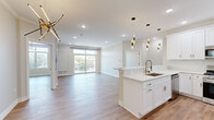 Located at 215 S Westmore Ave in Lombard, IL, this thoughtfully designed 2-bedroom, 2-bathroom residence offers a bright and modern living experience across a single floor. The open-concept layout seamlessly connects the kitchen and living room, creating an airy, expansive feel. Light wood-look flooring runs throughout, complemented by crown molding and recessed lighting.

The gourmet kitchen is a standout, featuring crisp white shaker cabinetry with gold hardware, marble-look quartz countertops, a marble tile backsplash, stainless steel appliances, and a large peninsula with a built-in sink and pendant lighting above. The living area opens to a private balcony through sliding glass doors, inviting natural light and outdoor views.

A dramatic accent wall with a built-in electric fireplace set against floor-to-ceiling marble-look tile serves as a striking focal point. The primary bedroom is generously sized, featuring crown molding, a modern ring chandelier, ambient LED lighting, and a dedicated closet with built-in rods. The bathrooms are elegantly appointed with marble-look tile flooring, navy vanities, quartz counters, and backlit mirrors. Two closets provide ample storage throughout the residence.