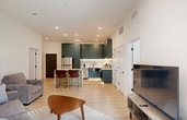 This thoughtfully designed 860-square-foot, single-floor apartment in Oz offers 2 bedrooms, 2 bathrooms, and a dedicated closet. The open-concept living room is bright and welcoming, featuring light hardwood-style flooring, recessed lighting, and large sliding glass doors that provide outdoor access and fill the space with natural light. The kitchen is a standout feature, showcasing bold teal flat-front cabinetry with brass hardware, a striking marble-veined waterfall island with bar seating, a herringbone tile backsplash, stainless steel appliances, and under-cabinet lighting. Both bathrooms are elegantly appointed with bold black-and-white geometric tile flooring, teal vertical subway tile in the showers, dark wood vanities with gold hardware, and large mirrors. The primary bedroom measures 140 square feet and offers carpeted flooring and generous proportions, while the second bedroom is equally comfortable. A dedicated closet features multi-tier wire shelving for ample storage. Throughout the unit, a cohesive modern aesthetic is maintained with neutral walls, clean lines, and carefully selected design details that balance style and functionality.