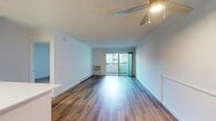 This 590 square foot apartment in Newport Beach offers a thoughtful blend of comfort and functionality. The single-floor layout comprises one bedroom, one bathroom, and an open-concept kitchen and living area. The kitchen is a highlight, featuring modern appliances, sleek white cabinetry, and a practical galley design. Stainless steel appliances, including a full-size refrigerator and range, enhance the contemporary aesthetic.

Throughout the apartment, warm wood flooring adds a touch of elegance and continuity. The living area is bright and airy, with sliding glass doors leading to a small balcony, providing natural light and a connection to the outdoors. The bedroom, measuring 180 square feet, offers ample space and includes a window for additional light and ventilation.

The bathroom is clean and modern, featuring a full-size bathtub with shower fixtures. White fixtures and tiling contribute to a fresh, spa-like ambiance. The apartment's efficient design maximizes the use of space, with thoughtful storage solutions evident in both the kitchen and bedroom areas. Overall, this apartment presents a turnkey living solution, ideal for those seeking a modern, low-maintenance home in the desirable Newport Beach area.