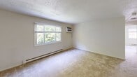 Located at 2 Winter St in Claremont, NH, this two-bedroom, one-bathroom unit offers a practical and well-organized single-floor layout. The space includes a living room, kitchen, two bedrooms, and a full bathroom, providing a functional arrangement for everyday living.

The kitchen features wood-look flooring, white cabinetry, and a full suite of white appliances including a refrigerator, electric range, and built-in microwave. A baseboard heating system runs throughout the unit, ensuring consistent warmth. Textured popcorn ceilings are a consistent architectural detail across all rooms.

The primary bedroom is a comfortable size, with carpet flooring, a wall-mounted air conditioning unit, and a large window that brings in natural light and views of surrounding greenery. A second bedroom also features carpet, a window with outdoor views, and a wall-mounted thermostat. A third carpeted room serves as an additional bedroom or flex space, with its own window and closet access.

The full bathroom is clean and functional, featuring a white tub/shower combo with chrome fixtures. Throughout the unit, neutral wall tones and carpeted floors create a calm, understated atmosphere. Multiple windows across the unit provide natural light and pleasant views of the neighborhood.