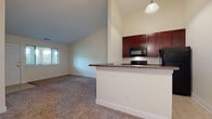 Located at 1003–1005 Eagle Dr in Green, Ohio, this single-floor unit offers a functional, well-organized layout with a neutral color palette throughout. The living area is generously proportioned, featuring warm beige carpet and cream-toned walls that create a bright, inviting atmosphere. A peninsula with granite countertops serves as the dividing element between the living space and kitchen, providing both a visual focal point and practical surface for dining or prep work.

The kitchen is efficiently designed with rich, dark cherry cabinetry extending to the upper walls for ample storage. Black appliances—including a refrigerator, electric range, and built-in microwave—complement the granite countertops and tile flooring. A pendant light fixture adds a finishing touch above the peninsula.

The bedrooms are carpeted and receive natural light through blinded windows, with views of surrounding greenery. Closet access is available in each room. The bathrooms feature light tile flooring, white vanities, and clean, minimalist fixtures, with one bathroom including an adjacent closet for additional storage convenience. Overall, the space maintains a consistent, understated aesthetic suited for comfortable everyday living.