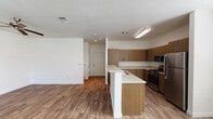 This two-story residence is designed with a practical and modern layout that balances functionality and comfort throughout both levels. The main living area on the ground floor is open and airy, with wood-look flooring that flows seamlessly from the living room through the dining area and into the kitchen. Large windows allow generous natural light to fill the space, and a chandelier above the dining area adds a refined touch.

The kitchen is well-appointed, featuring warm medium-toned wood cabinetry, granite-look countertops, and stainless steel appliances including a gas range, microwave, and refrigerator. A peninsula with a built-in sink provides additional prep space and serves as a natural divider between the kitchen and living areas. A compact half bathroom with a pedestal sink is also located on the main floor, offering added convenience for guests.

The attached garage includes an in-unit washer and dryer, adding everyday practicality. Upstairs, the bedrooms are carpeted and well-sized, each with standard closet access. The full bathroom features wood-look flooring, a granite-topped vanity with wood cabinetry, and a combined tub and shower. The overall aesthetic is clean and contemporary, with a neutral palette throughout.