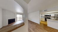 This single-floor residence offers a thoughtfully designed layout with a clean, modern aesthetic throughout. The open living area is anchored by a classic fireplace with a raised hearth and flows seamlessly toward a sliding glass door that opens to a private balcony, filling the space with natural light and outdoor views. Wood-look flooring runs throughout the main living areas, complementing the crisp white walls and textured ceilings.

The kitchen is a standout feature, showcasing white cabinetry, a tile backsplash, stainless steel appliances including a range, over-the-range microwave, and refrigerator, as well as a peninsula with a marble-style quartz countertop and a gold-finish sink faucet. A stylish pendant light overhead adds a contemporary touch. The peninsula provides a natural transition into the dining and living spaces, making it ideal for both cooking and entertaining.

The bathroom is finished with a white vanity topped with a quartz-style countertop, a full tub and shower combination, and wood-look flooring that ties in with the rest of the unit. A dedicated in-unit laundry area accommodates a full-size washer and dryer side by side, with an overhead storage shelf for added convenience. The overall layout is functional, well-lit, and move-in ready.