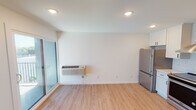 Located at 2823 S Wayzata Blvd in Minneapolis, Minnesota, this single-floor unit offers a clean, modern aesthetic with thoughtfully updated finishes throughout. The open living area features light-toned hardwood-style flooring and crisp white walls, creating a bright and airy atmosphere. A sliding glass door allows natural light to filter in while providing access to the outdoors.

The kitchen is a standout feature, showcasing white shaker-style cabinetry with matte black hardware, white quartz countertops, and a herringbone-patterned tile backsplash. Stainless steel appliances include a full-size refrigerator and an electric range complemented by a sleek stainless chimney hood, along with a matte black faucet over a undermount sink.

The bedroom area offers a clean, open space with the same consistent flooring and neutral walls, providing a versatile canvas. A dedicated laundry room includes a stacked Bosch washer and dryer along with wire shelving for added storage convenience.

The bathroom is well-appointed with a gray vanity, white quartz countertop, matte black fixtures, a tub-shower combination, and matching hardwood-style flooring. Recessed lighting throughout the unit adds a polished, contemporary feel. A wall-mounted HVAC unit ensures individualized climate control.