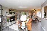 This single-floor home offers a thoughtfully designed layout with warm, neutral tones and wood-look flooring throughout. The living room serves as a central gathering space, anchored by a striking stone fireplace with a white mantle and tile hearth. Large sliding glass doors provide access to an outdoor deck while filling the room with natural light and views of surrounding greenery. A built-in shelving unit adds functional display space to the living area.

The dining room sits adjacent to the living space, featuring a ceiling fan with lighting, vertical blinds on multiple windows, and a sliding door to the deck, creating a bright and airy atmosphere well-suited for everyday dining.

The kitchen is equipped with rich dark espresso cabinetry, granite-style countertops, a classic white subway tile backsplash, a double stainless steel sink, and black appliances, offering ample storage and counter space.

Multiple bedrooms provide comfortable retreats, each featuring ceiling fans, vertical blinds, wood-look flooring, and closet storage. The bathrooms include a full bath with a tub-shower combination and dark vanity cabinetry, as well as a separate water closet, offering practical functionality throughout.