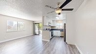 Located at 837-845 16th St in San Diego, CA, this thoughtfully updated 3-bedroom, 2-bathroom unit offers a comfortable and functional single-floor layout. Light-toned luxury vinyl plank flooring runs throughout, tying together a clean, modern aesthetic. The open living area is bright and airy, enhanced by a ceiling fan and a sliding glass door that leads to a private balcony with urban and treetop views. The kitchen is well-appointed with white shaker cabinetry, dark quartz countertops, a skylight, and a full suite of stainless steel appliances including a range, microwave, dishwasher, and refrigerator. Three bedrooms offer neutral tones and natural light via slatted blinds; the primary bedroom includes its own ceiling fan and balcony access with city views. Two hallways connect the living spaces efficiently. The bathrooms are cleanly finished, with one featuring a tub-shower combo with white tile surround and dark quartz vanity, and the other offering a walk-in shower with brushed nickel fixtures. Textured ceilings and crisp white trim complete the interior. The layout makes efficient use of its footprint while maintaining a bright, livable feel.