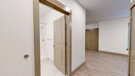 Located at 133 S East St in Amherst, Massachusetts, this efficiently designed single-floor unit offers a thoughtful layout that maximizes every square foot. Light wood-look flooring runs continuously throughout the space, creating a cohesive and clean aesthetic. Crisp white walls and flush-mounted ceiling lighting contribute to a bright, welcoming ambiance.

The open living area provides a flexible space accented by a wall-mounted mini-split HVAC unit for year-round comfort, along with a window fitted with blinds that allows natural light to filter in. A set of double doors leads to a closet, adding practical storage to the living space.

The kitchen is equipped with dark gray cabinetry, granite-style countertops, a stainless steel refrigerator, a dishwasher, and a sink — offering a fully functional cooking environment despite its compact footprint. Recessed lighting illuminates the kitchen corridor neatly.

The bathroom is finished in a clean, minimal style with large-format tile flooring, a walk-in shower featuring a built-in grab bar and chrome fixtures, and a toilet. The tan two-panel doors found throughout the unit add a subtle warm contrast to the otherwise neutral interior palette, tying the design together with a consistent and polished look.