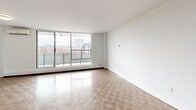 Located at 35 Walmer Rd in Toronto's sought-after Annex neighbourhood, this well-appointed 2-bedroom, 1-bathroom unit offers a comfortable and functional layout across a generous floor plan. Distinctive parquet wood flooring runs throughout the living areas and bedrooms, lending warmth and character to the space.

The open-concept kitchen and living room form the heart of the unit. The kitchen is equipped with stainless steel appliances, including a refrigerator, stove, and built-in microwave, complemented by white cabinetry, a tiled backsplash, dark countertops, and a peninsula island that provides additional prep and storage space. The adjoining living room is bright and spacious, featuring large sliding glass doors that open onto a private balcony with open views of the Toronto skyline and surrounding neighbourhood.

Both bedrooms are well-sized, with the primary bedroom offering a window framing city views and baseboard heating. The bathroom is finished with classic white subway tile surrounding a full soaker tub and shower combination, paired with chrome fixtures for a clean, timeless look.

Two hallways connect the rooms efficiently, and a wall-mounted air conditioning unit services the living area. The unit's clean white walls and abundant natural light create a bright, neutral canvas throughout.