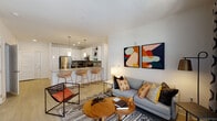Located at 411 Flemington Rd in Chapel Hill, NC, this contemporary single-floor residence offers a well-designed open-concept layout that seamlessly connects the living, dining, and kitchen areas. The kitchen is outfitted with sleek white cabinetry, stainless steel appliances, a subway tile backsplash, and a granite-topped island with bar seating, illuminated by stylish pendant lighting. Light wood-style flooring flows throughout, complementing the clean, bright aesthetic of the space. The living area is bathed in natural light through large floor-to-ceiling windows and sliding glass doors that open onto a private balcony, extending the living space outdoors. The bedroom is generously sized, featuring a ceiling fan, a large window with exterior views, and direct access to a full bathroom. The bathroom includes a tub-shower combo with white subway tile surround, paired with a built-in linen closet for added convenience. Multiple walk-in closets provide ample storage, equipped with wire shelving systems and light wood flooring. Throughout the residence, neutral walls and recessed lighting create a versatile, modern ambiance well-suited to a variety of lifestyles.