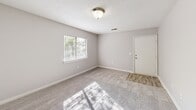 Located at 1528 S Mebane St in Burlington, NC, this two-bedroom, one-bathroom unit offers a practical and well-organized single-floor layout. The open-concept living, dining, and kitchen area forms the heart of the home, with soft carpet throughout the living space and wood-look flooring at the entryway. The kitchen features white cabinetry, dark granite-style countertops, black appliances including a refrigerator and range, and a peninsula that provides additional prep space and separates the kitchen from the living and dining area. Natural light filters in through windows fitted with horizontal blinds, offering pleasant outdoor greenery views. The two carpeted bedrooms are comfortably sized, each featuring a window and dedicated closet space. The primary bedroom is a solid size and connects conveniently to the hallway. The full bathroom includes a tub-shower combination with clean white surround. Additional practical features include an in-unit laundry area and a patio for outdoor access. Textured ceilings are consistent throughout the unit, and the neutral gray-toned walls provide a clean, versatile backdrop throughout the space.