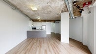 Located on Rue Sherbrooke Est in Montréal's Ville-Marie district, this unit blends industrial character with modern finishes in a well-designed single-floor layout. The open-concept living and kitchen area serves as the heart of the space, where exposed concrete ceilings with visible ductwork and structural beams create a distinctive loft-like aesthetic. Light-toned hardwood flooring runs throughout, lending warmth and continuity to the space. Natural light filters in through large windows that frame views of surrounding greenery, enhancing the airy, open feel of the living area, which also features a structural column that adds to the industrial charm.

The kitchen is thoughtfully appointed with sleek white upper cabinetry, dark wood-tone lower cabinets, and light quartz countertops extending into a peninsula with an undermount sink. Stainless steel appliances — including a range, refrigerator, dishwasher, and built-in microwave — complete the functional cooking space, finished with a subtle tile backsplash.

The bathroom is clean and efficiently designed, featuring large-format light tiles, a dark vanity with a white countertop, a full bathtub with overhead shower, and crisp white walls that maximize the sense of brightness. Overall, this unit offers a compelling mix of urban industrial style and contemporary comfort in a central Montréal location.