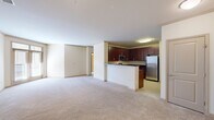 This 2-bedroom, 2-bathroom residence is designed for comfortable, functional living across a single floor. The open-concept layout connects the living area to the kitchen, which is outfitted with rich dark cherry cabinetry, dark granite countertops, a peninsula breakfast bar, and a full suite of stainless steel appliances including a gas range, built-in microwave, dishwasher, and refrigerator. Light tile flooring anchors the kitchen, while soft neutral carpet flows throughout the living areas and bedrooms, creating a warm, cohesive aesthetic. Crown molding accents the main living spaces, adding a refined architectural detail. The primary bedroom is generously sized and includes a walk-in closet with wire shelving for ample organization. A second bedroom and additional closet provide flexibility for guests or a home office. Both bathrooms feature clean, classic finishes with tile flooring; one includes a soaking tub and shower combination. A dedicated in-unit laundry room houses a full-size stacked washer and dryer. Two hallways connect the layout efficiently, and neutral warm-toned walls throughout contribute to a bright, move-in-ready ambiance.