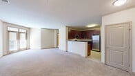 This 2-bedroom, 2-bathroom residence is designed for comfortable, functional living across a single floor. The open-concept layout connects the living area to the kitchen, which is outfitted with rich dark cherry cabinetry, dark granite countertops, a peninsula breakfast bar, and a full suite of stainless steel appliances including a gas range, built-in microwave, dishwasher, and refrigerator. Light tile flooring anchors the kitchen, while soft neutral carpet flows throughout the living areas and bedrooms, creating a warm, cohesive aesthetic. Crown molding accents the main living spaces, adding a refined architectural detail. The primary bedroom is generously sized and includes a walk-in closet with wire shelving for ample organization. A second bedroom and additional closet provide flexibility for guests or a home office. Both bathrooms feature clean, classic finishes with tile flooring; one includes a soaking tub and shower combination. A dedicated in-unit laundry room houses a full-size stacked washer and dryer. Two hallways connect the layout efficiently, and neutral warm-toned walls throughout contribute to a bright, move-in-ready ambiance.