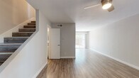 This two-story residence offers a clean, modern aesthetic highlighted by warm luxury vinyl plank flooring that runs consistently throughout both levels. The open main living area is bright and spacious, anchored by a ceiling fan and a sliding glass door that fills the room with natural light and provides access to an outdoor patio area. Adjacent to the living space, the updated kitchen is a standout feature, showcasing a peninsula with a dark quartz countertop and integrated stainless steel sink, white shaker-style cabinetry, a classic subway tile backsplash, and stainless steel appliances including a gas range and over-the-range microwave. Multiple windows bring in additional natural light and outdoor views. The bedrooms are generously proportioned, each equipped with ceiling fans and windows that invite natural light. At least one bedroom includes a dedicated closet with ample storage space. The bathroom is finished with large-format marble-look tile in the tub and shower surround, complemented by wood-look tile flooring and brushed nickel fixtures, lending a refined, contemporary feel. The entry level features a welcoming foyer with staircase access to the upper floor, completing this well-appointed multi-level home.