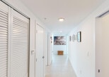 Located at 1951 NW South River Dr in Miami, FL, this single-floor residence offers a clean, modern aesthetic defined by crisp white walls, light tile flooring, and an abundance of natural light throughout. A wide, well-lit hallway lined with framed artwork serves as a welcoming entry point, connecting the various living spaces with ease.

The contemporary kitchen is thoughtfully designed with warm wood cabinetry, frosted glass upper cabinets, granite countertops, and a full suite of stainless steel appliances including an electric range, built-in microwave, and refrigerator. A peninsula counter extends the workspace and provides an informal dining or prep area.

The living area features an open, airy layout with light-toned tile flooring and a relaxed, coastal-inspired atmosphere. The primary bedroom is generously sized with plush carpeting, sliding glass doors opening to a private balcony with panoramic Miami city views, and direct access to a walk-in closet. A second bedroom also benefits from large windows framing expansive outdoor views. Both bathrooms are finished with neutral stone-toned tile, soaking tub-shower combinations, and vanities with ample counter space. The overall ambiance is bright, calm, and sophisticated — well-suited to the vibrant Miami lifestyle.