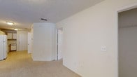 Located at 101 Leeward Ln in Hampstead, NC, this single-floor residence offers a straightforward and functional layout designed for comfortable everyday living. The interior is finished in a clean, neutral palette of crisp whites and warm beige tones, creating a bright and cohesive atmosphere throughout.

The living area is generously sized, featuring plush wall-to-wall carpeting and textured ceilings, providing a comfortable and understated setting. The kitchen is well-equipped with white cabinetry offering ample storage, white appliances including a range, microwave, and dishwasher, and durable tile flooring. A door in the kitchen provides convenient exterior access.

The bedrooms are carpeted and bathed in natural light from windows fitted with blinds. Each bedroom includes a closet with built-in shelving for organized storage, and at least one room features a ceiling fan for added comfort. The hallway connects the rooms with an efficient flow throughout the single-floor plan.

The bathroom is cleanly appointed with a vanity, single-sink, tile flooring, a towel bar, and a tub-shower combination. The space as a whole is move-in ready, presenting a tidy and well-maintained environment suited for a variety of occupants in the coastal Hampstead, NC community.