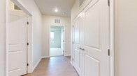 This single-floor unit offers a clean, contemporary design highlighted by a neutral color palette and light wood-style flooring that flows through the main living areas. The open-concept kitchen serves as a central hub, featuring white cabinetry, a center island with a white countertop, and a full suite of stainless steel appliances including a refrigerator, range, microwave, and dishwasher. The kitchen connects seamlessly to the living area, which benefits from large windows that draw in generous natural light and provide outdoor views of surrounding greenery and streetscapes.

The bedrooms are well-proportioned, with plush carpet flooring and oversized windows that frame outdoor views. At least one bedroom includes access to a walk-in closet with built-in shelving, offering practical storage solutions. A secondary bedroom features direct access to an exterior door.

The unit includes two bathrooms. One features a walk-in shower with grab bar, a white vanity, and wood-style flooring. The second bathroom offers a larger vanity with gray cabinetry, a tall storage tower, and a well-lit mirror. A hallway connects the private areas of the unit, featuring a panel-style door and ceiling vents for climate control, contributing to the home's clean, functional aesthetic throughout.