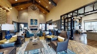 Located at 100 Oakview Dr in Trumbull, CT, this single-floor community clubhouse is a masterfully designed amenity space that combines architectural grandeur with sophisticated interior finishes. The centerpiece is a soaring great room with vaulted wood-beam ceilings, a striking floor-to-ceiling stacked-stone fireplace, and herringbone-patterned hardwood flooring. Plush leather and velvet seating arrangements, layered area rugs, and curated decorative accents create a warm yet refined atmosphere. Steel-framed glass partition walls divide the space elegantly while maintaining visual openness throughout.

A dedicated dining area features exposed dark wood beams, a statement chandelier, and full-height sliding glass doors that open directly to an outdoor patio, seamlessly blending indoor and outdoor living. The private screening room is outfitted with tiered leather recliner seating, a large projection screen, and ambient LED cove lighting — offering a true cinematic experience.

A stylish game lounge includes a marble-topped island with bar seating, brick accent walls, and open shelving stocked for entertaining. A functional kitchenette with light wood cabinetry, dark countertops, and stainless steel appliances provides convenient support for events. A separate lounge nook with mosaic tile accent walls and built-in shelving rounds out this exceptional amenity hub.