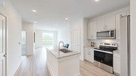 Located at 3025 Woodward Crossing Blvd in Buford, GA, this well-appointed one-bedroom, one-bathroom residence offers a clean, modern aesthetic throughout its thoughtfully designed single-floor layout. The open-concept kitchen and living area serves as the heart of the home, anchored by a central granite-topped kitchen island with an undermount sink. White shaker cabinetry reaches toward the ceiling, complemented by a subway tile backsplash, stainless steel appliances including a range, over-the-range microwave, and refrigerator. Light wood-tone flooring flows seamlessly through the main living areas, enhancing the bright, airy atmosphere created by recessed lighting and abundant natural light. The living room opens directly onto a private balcony through sliding glass doors, offering peaceful outdoor views of surrounding greenery. The bedroom features plush carpeting, a ceiling fan, and a large window that frames natural views. The full bathroom impresses with a dual-sink granite vanity, generous cabinetry, and a full soaking tub with tile surround. A dedicated in-unit laundry room with full-size washer and dryer hookups and built-in shelving adds everyday convenience, rounding out this functional and stylish residence.