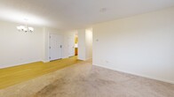 Located at 5945 Vinecroft Dr in Clarence Center, NY, this single-floor, two-bedroom, one-bathroom residence offers a practical and comfortable layout. The open living area features a mix of light hardwood-style flooring at the entry and soft carpeting throughout, with multiple windows dressed in neutral curtains that allow generous natural light and views of the surrounding neighborhood. Wall-unit HVAC units are present in the living and bedroom areas for efficient climate control. The kitchen is well-equipped with warm oak cabinetry, white laminate countertops, a stainless steel sink, and white appliances including an electric range and microwave, all set on light wood-style flooring. The primary bedroom is generously sized and includes two closets—one of which is a spacious walk-in—providing ample storage. The second bedroom is cozy and also features a window with outdoor views and its own wall unit. The full bathroom is finished with tile-style flooring and includes accessibility features such as grab bars near the toilet and shower area. Two dedicated closets throughout the unit further enhance storage. The overall aesthetic is clean, neutral, and move-in ready.