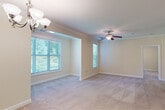 This single-floor residence offers a thoughtfully designed layout that balances comfort and functionality throughout. The open living and dining areas are finished with plush wall-to-wall carpeting and warm neutral tones, with crown molding and elegant chandelier lighting adding a refined touch. Multiple windows fitted with blinds allow abundant natural light to fill the space while offering views of lush greenery outside. A ceiling fan in the living area enhances comfort year-round.

The galley-style kitchen is well-equipped, featuring warm wood cabinetry, granite-style countertops, a double stainless steel sink, and black appliances including a range, microwave, refrigerator, and dishwasher. Light tile flooring and pendant lighting complete the kitchen's practical yet inviting character.

The bedrooms are generously proportioned, each with soft carpeting, neutral walls, and ample natural light. The primary bedroom benefits from a ceiling fan, multiple windows, and direct access to a spacious walk-in closet with wire shelving. The adjoining bathroom is finished with tile flooring, warm wood vanity cabinetry, granite countertops, and a clean, functional layout. A dedicated laundry area with washer and dryer hookups adds everyday convenience to this well-rounded home.