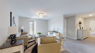 This single-floor residence on Judge Carden Blvd in Crestwood, Kentucky, offers a thoughtfully designed layout with a neutral color palette and quality finishes throughout. The living area is a welcoming space featuring wood-look flooring, soft gray walls, and a glass-panel door that allows natural light to filter in while providing access to an outdoor area. The open arrangement comfortably accommodates multiple seating areas, lending the room a versatile and airy feel.

The galley-style kitchen is efficiently organized with dark espresso cabinetry lining both walls, light quartz countertops, and a full suite of stainless steel appliances, including a refrigerator, range, and microwave. Wood-look flooring continues here, maintaining a cohesive aesthetic.

The bedrooms are carpeted for comfort, each offering generous proportions, neutral walls, and windows that bring in natural light. The bathrooms feature dark vanity cabinetry paired with white countertops and wood-look flooring. One bathroom includes a walk-in shower with built-in shelving, while a secondary bath offers a more compact configuration. A dedicated laundry room with side-by-side washer and dryer hookups and overhead shelving adds practical convenience to this well-rounded home.
