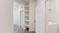 This thoughtfully designed 2-bedroom, 2-bathroom residence in Centennial, CO offers a clean, modern aesthetic with an open-concept layout that maximizes functionality and flow. The kitchen serves as the heart of the home, showcasing a generous center island with a dark countertop, a deep single-basin sink, stainless steel appliances including a refrigerator, microwave, and range, and crisp white cabinetry with a subway tile backsplash. Recessed lighting illuminates the space, which opens seamlessly into the living area bathed in natural light from multiple windows. Light hardwood-style flooring runs throughout the main living areas, complementing the neutral white walls for a bright, cohesive look. The spacious primary bedroom features a ceiling fan, a large window with exterior views, and ample room for furnishings. The second bedroom also benefits from generous natural light through a wide window. Both bathrooms are finished with white cabinetry, dark countertops, and clean tile work, with one featuring a full tub-shower combo. Built-in shelving in the hallway provides additional storage, and an in-unit laundry area adds everyday convenience. Three closets throughout the unit offer plentiful storage for residents.