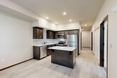 This well-designed 2-bedroom, 2-bathroom residence in Arlington, WA offers a thoughtful single-floor layout that maximizes every square foot of living space. The open-concept living area seamlessly connects the kitchen, dining, and living spaces, creating an inviting and functional hub for daily life. The kitchen is a standout feature, outfitted with dark espresso cabinetry, white quartz countertops, a subway tile backsplash, stainless steel appliances including a refrigerator, range, microwave, and dishwasher, and a center island that provides additional prep space and casual seating. Light wood-tone luxury vinyl plank flooring runs throughout the main living areas, adding a clean, contemporary look. A hallway connects the bedrooms and bathrooms, offering a sense of separation and privacy. The primary bedroom is a comfortable retreat with plush carpet, a window for natural light, and access to a walk-in closet equipped with wire shelving. The second bedroom is similarly carpeted and well-lit. Both bathrooms feature dark wood vanities with white countertops and light tile flooring, with one including a tub-shower combination and the other conveniently housing a stacked in-unit washer and dryer. Three closets throughout the unit provide generous storage.
