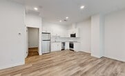 Located at 10029 108 Street NW, this thoughtfully designed single-floor unit offers a clean, modern aesthetic throughout. Light-toned luxury vinyl plank flooring runs continuously across all areas, complementing the crisp white walls and recessed lighting to create a bright, cohesive interior.

The open-concept living and kitchen area serves as the heart of the unit. The kitchen is well-appointed with white shaker-style cabinetry extending to the ceiling, a subway tile backsplash, stainless steel appliances including a refrigerator, dishwasher, electric range, and built-in microwave, along with a undermount sink. The layout makes efficient use of the available space without feeling cramped.

A large storefront-style window and glass entry door face the street, flooding the front area with natural light while roller shades provide privacy when needed. Double interior doors lead further into the unit from this entry zone.

The bedroom is a quiet, functional space featuring a sliding-door closet with wire shelving for organized storage. The bathroom is finished in clean white tiling with a full soaker tub and shower combination. A dedicated laundry area accommodates a stacked washer and dryer unit, adding significant convenience to daily living.