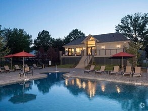 Swimming pool surrounded by lounge chairs with the Yardley Crossing clubhouse in the back at dusk - Yardley Crossing Luxury Apt and Townhomes