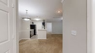 Located at 1022 Level Creek Road in Sugar Hill, Georgia, this two-bedroom, two-bathroom residence offers a comfortable and well-organized single-floor layout. The living area features plush carpeting, crown molding, and a ceiling fan, with sliding glass doors that invite natural light and provide outdoor access. The kitchen is efficiently designed with gray cabinetry, a tile backsplash, white countertops, and black appliances, including a refrigerator, dishwasher, stovetop, and microwave. Wood-look flooring runs through the kitchen and bathrooms, creating a clean contrast to the carpeted living and sleeping areas. The primary bedroom is a generous, well-proportioned retreat complete with crown molding, a ceiling fan, a walk-in closet with built-in shelving, and a private en-suite bathroom featuring gray vanity cabinetry and a shower. The second bedroom also features a ceiling fan and a large window with views of surrounding greenery. The second bathroom includes a full tub-shower combination and matching gray vanity. A dedicated laundry area houses a full-size washer and dryer with overhead shelving for added storage convenience.