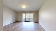 Located in Orlando, FL, this thoughtfully designed 1-bedroom, 1-bathroom residence offers a comfortable and functional layout across a single floor. The living room is a bright, open space featuring light wood-style flooring, neutral-toned walls, and a textured ceiling. A large sliding glass door floods the room with natural light and opens onto a private balcony overlooking a lush, wooded backdrop — creating a serene, nature-filled atmosphere. The dining area sits adjacent to the kitchen, connected via a pass-through window with a granite-style countertop, making the space feel open and connected. The kitchen is equipped with slate-blue cabinetry, light stone countertops, stainless steel appliances including a refrigerator, dishwasher, and range, all set over light hardwood-style flooring. The spacious primary bedroom features plush carpeting, a ceiling fan, a natural-light window, and access to two closets, offering ample storage. The full bathroom includes a combined tub and shower, a vanity with matching cabinetry, and light flooring consistent with the rest of the home. Hallways connect the rooms efficiently, completing a well-organized and move-in-ready living space.