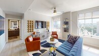 This thoughtfully designed single-floor residence blends contemporary style with functional living across its well-appointed spaces. The living room serves as a vibrant centerpiece, featuring light-toned flooring, a ceiling fan, and large windows that invite natural light and offer urban views. Bold décor choices — including a striking gold sculptural wall installation, cognac leather accent chairs, and a deep navy sectional sofa atop a graphic area rug — give the space a curated, upscale character.

The open-concept kitchen is a standout, outfitted with sleek flat-front cabinetry in a warm grey wood finish, quartz countertops, and a central island with bar seating for two. Stainless steel appliances, a subway tile backsplash, and a trio of smoked glass pendant lights complete the modern aesthetic, while generous windows flood the space with natural light.

The bedroom offers a calm retreat, with neutral walls, light flooring, a ceiling fan, and a window with open city views providing a peaceful backdrop. The bathroom is equally refined, featuring wood-toned cabinetry, a quartz vanity, a backlit frameless mirror, and a glass-enclosed walk-in shower — all finished in a cohesive, contemporary palette that ties the residence together seamlessly.