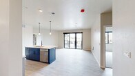 This well-appointed 2-bedroom, 2-bathroom residence is spread across a single floor, offering a practical and modern layout. The open-concept kitchen and living area serves as the heart of the home, featuring a central island with a sink and bold navy cabinetry, complemented by stainless steel appliances including a dishwasher, electric range, microwave, and refrigerator. Light taupe upper cabinetry with white quartz-style countertops completes the kitchen's contemporary aesthetic. Light wood-style vinyl plank flooring runs throughout the main living areas, adding warmth and continuity. Sliding glass doors in the living area provide access to an outdoor balcony and invite natural light into the space. The generously sized primary bedroom features plush carpeting and is accompanied by a spacious walk-in closet with built-in wire shelving. The second bedroom also features carpet flooring and a large window with outdoor views. Both bathrooms are finished with light wood-style flooring, white soaking tub-shower combos, undermount sinks, white countertops, and modern matte black fixtures. A dedicated laundry room houses a full-size washer and dryer. Neutral wall tones and clean lines throughout give this residence a bright, move-in-ready feel.